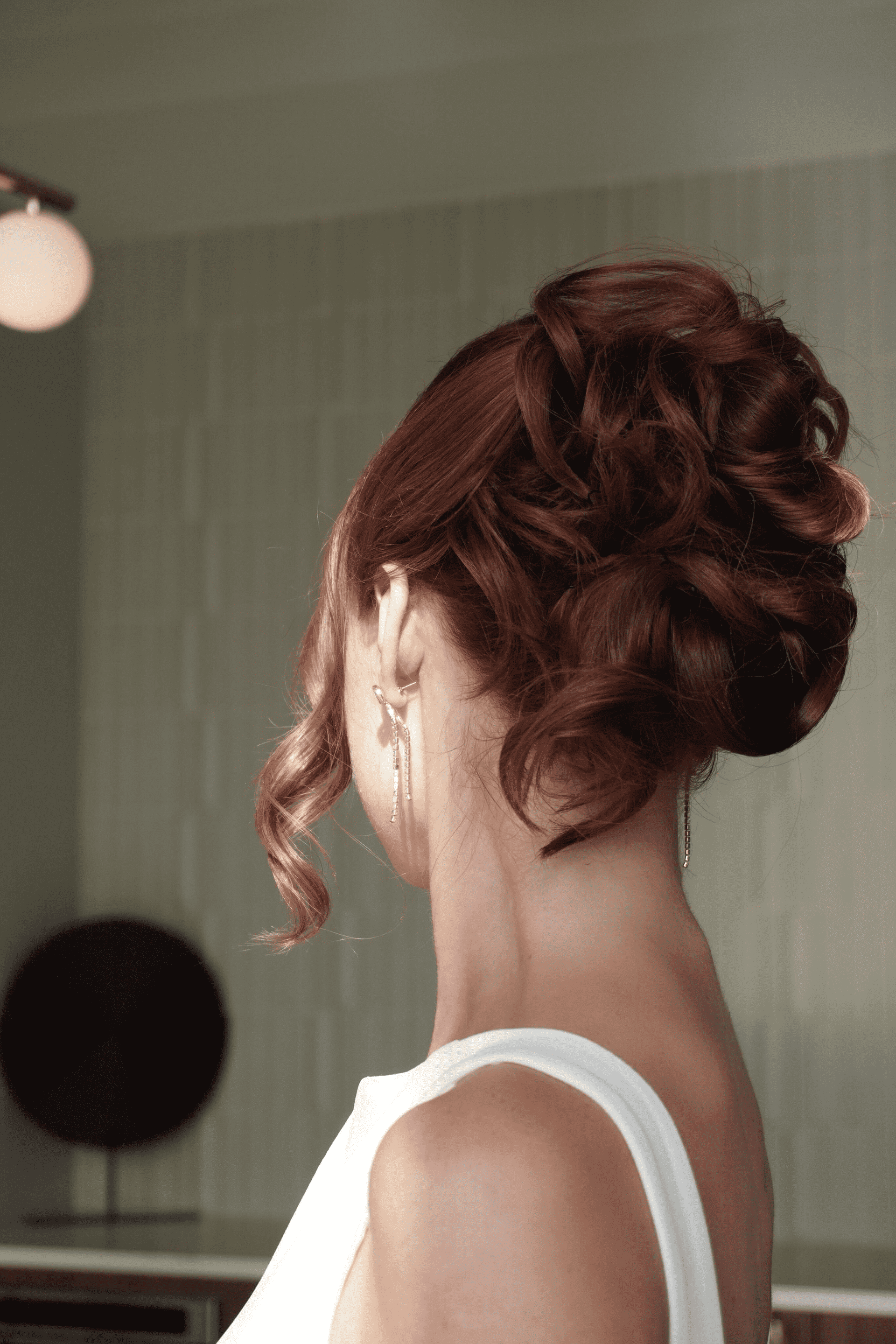 Red-haired woman with an elegant updo hairstyle in a white dress.