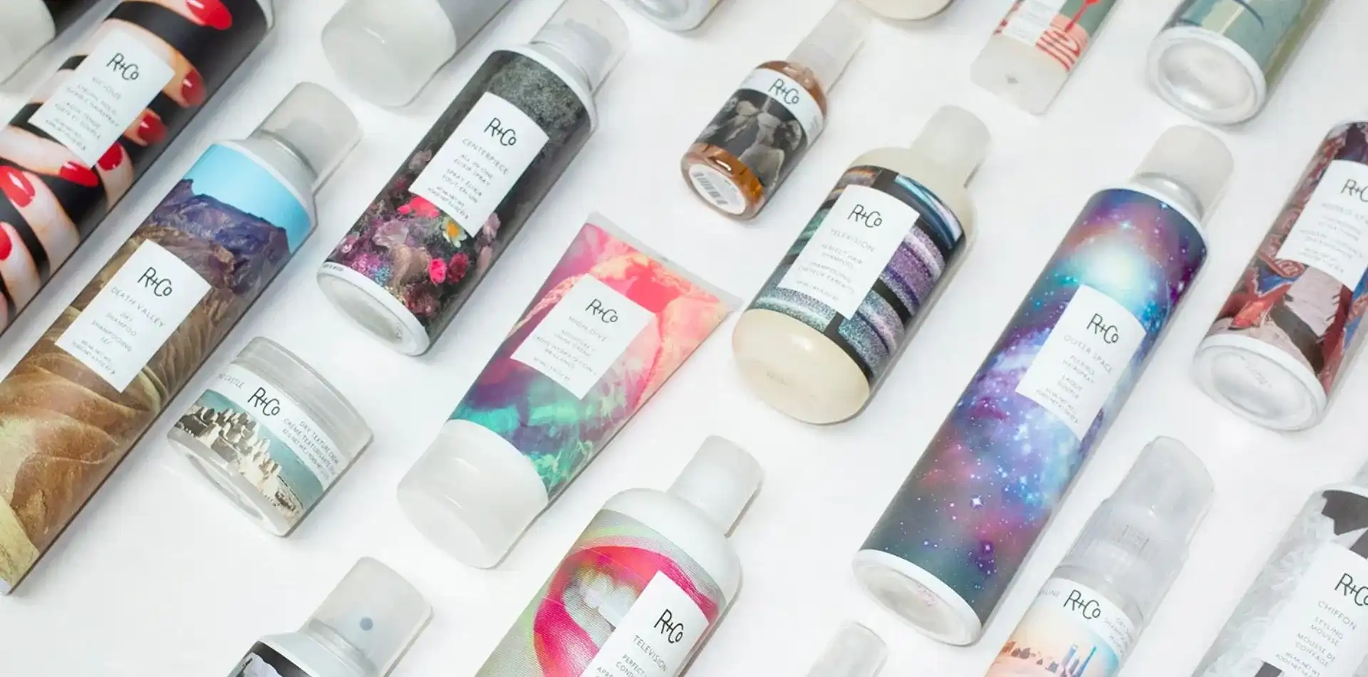 Array of R+Co hair care products with colorful, artistic packaging designs.